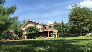 A two-story wooden house with a balcony, surrounded by a well-maintained lawn and trees. - Modern house, Hot Tube, lakes, pools, water parks, Ski, tennis A/C Free WiFi (Albrightsville)