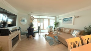 Un salón amplio con televisor, comedor con sillas, sofá y mesa de centro.