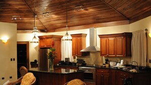 A kitchen with wooden cabinets, a central island, and pendant lighting.
