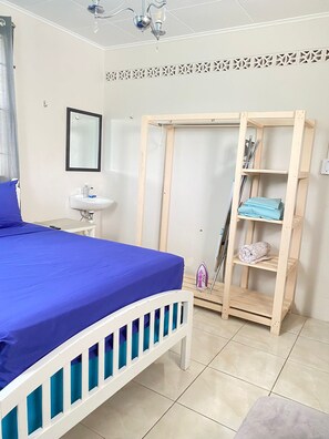 Un dormitorio con cama, mesita de noche, espejo, armario e iluminación en el techo.