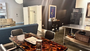 Una cocina moderna con zona de comedor, que incluye una mesa de mármol, sillas, un sofá y un mueble con utensilios de cocina.