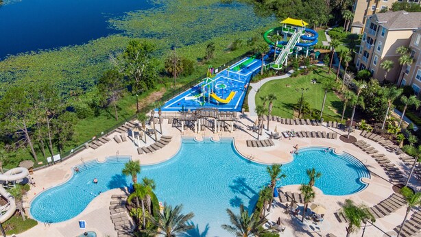 A resort with a large pool, a water park, and a well-maintained lawn area.