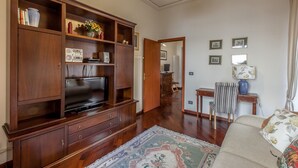 A living room with a wooden entertainment center, a television, a patterned rug, and a sofa.