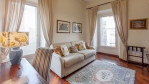 A living room with a sofa, a patterned rug, and curtains.