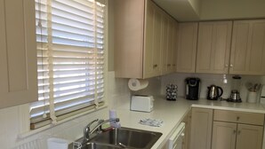 Una cocina con un lavamanos de acero inoxidable, un tostador, una cafetera y un hervidor.