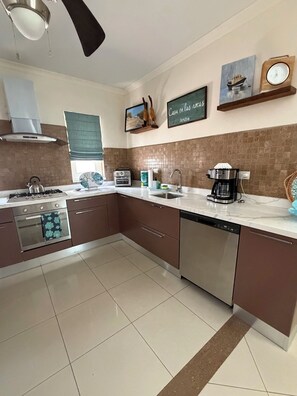 A modern kitchen with a gas stove, oven, dishwasher, and a coffee maker.