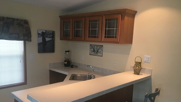 A kitchen with a large island, wooden cabinets, a blender, and a sink. - Wild Rose Ranch Guest Cabin (Baraboo)
