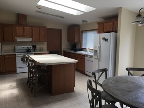 A kitchen with wooden cabinets, a central island, a stove, and a refrigerator.
