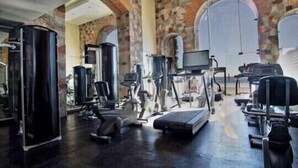 Une salle de sport équipée de divers appareils d’exercice, notamment des tapis de course et des appareils de musculation, et dotée d’un grand mur entièrement recouvert de miroirs.