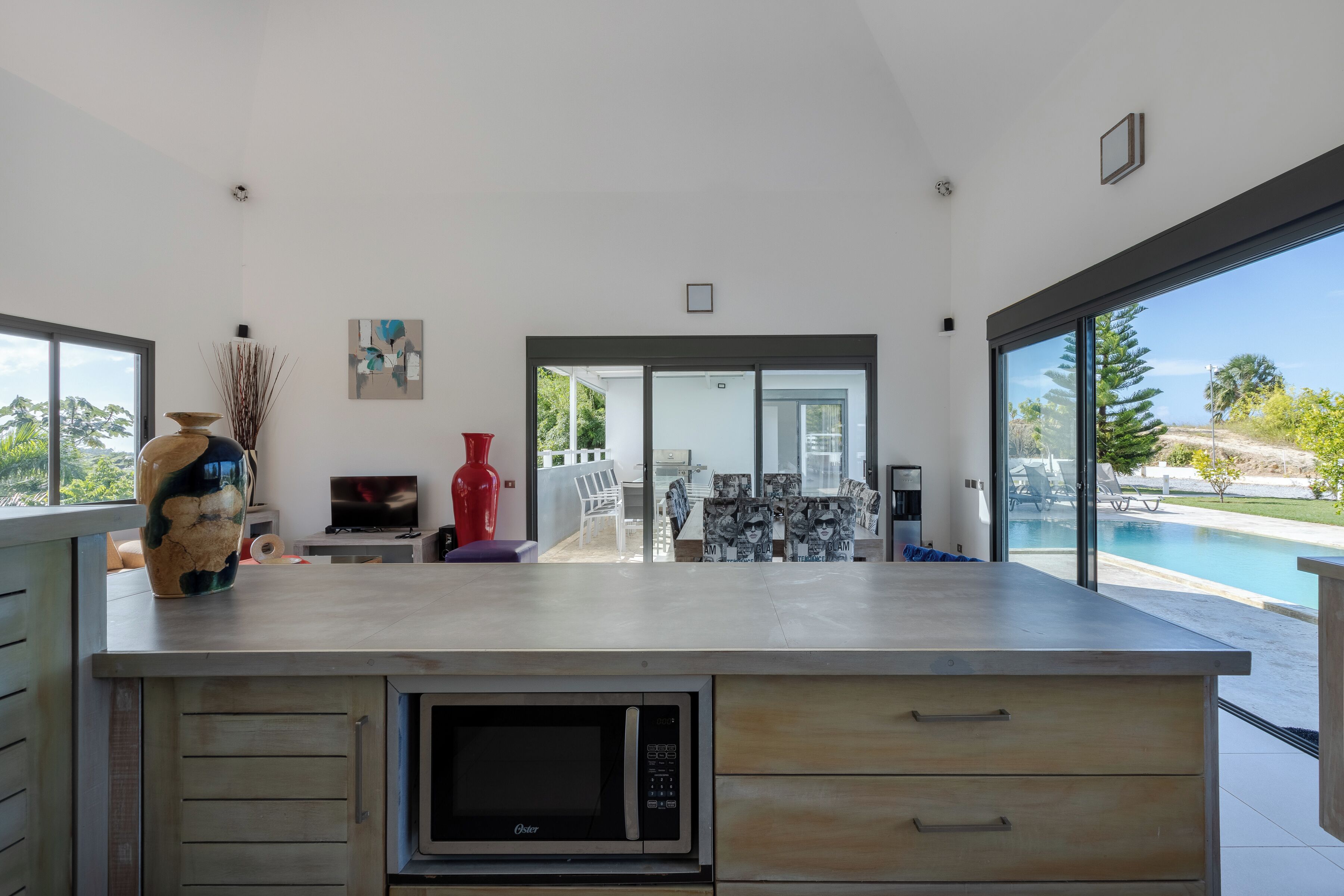 A modern kitchen with a built-in microwave, a large island, and a view of a swimming pool.