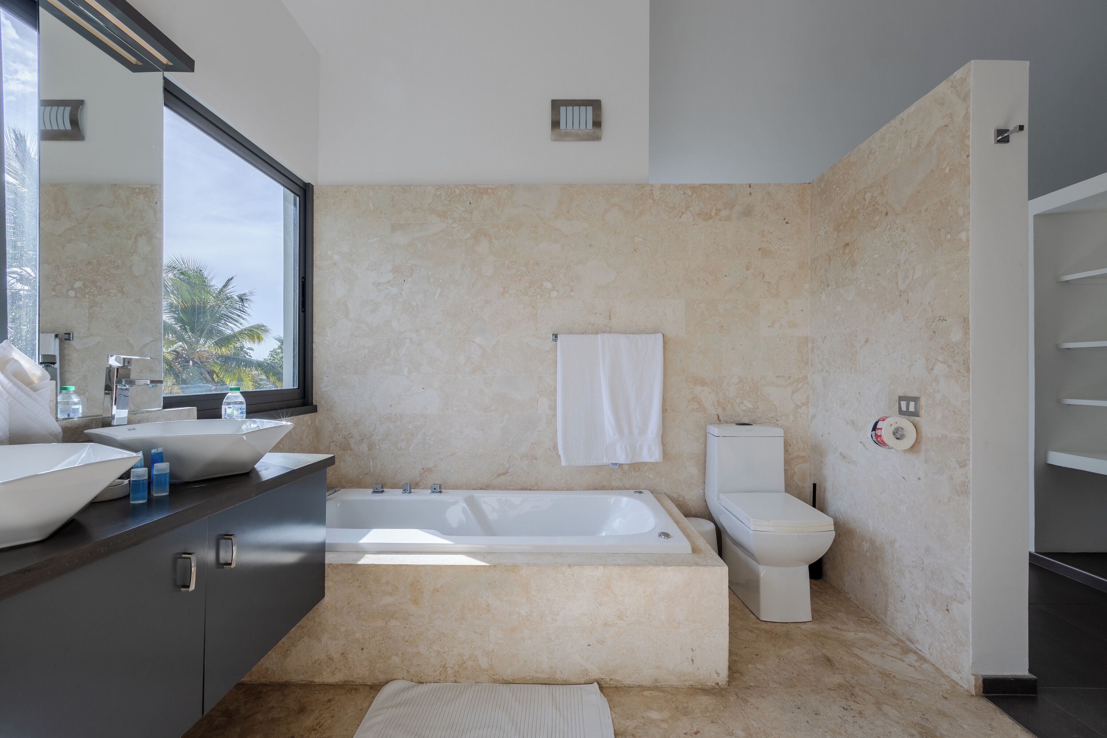 Une salle de bain moderne avec une grande baignoire, des toilettes et un lavabo surmonté d’un miroir.