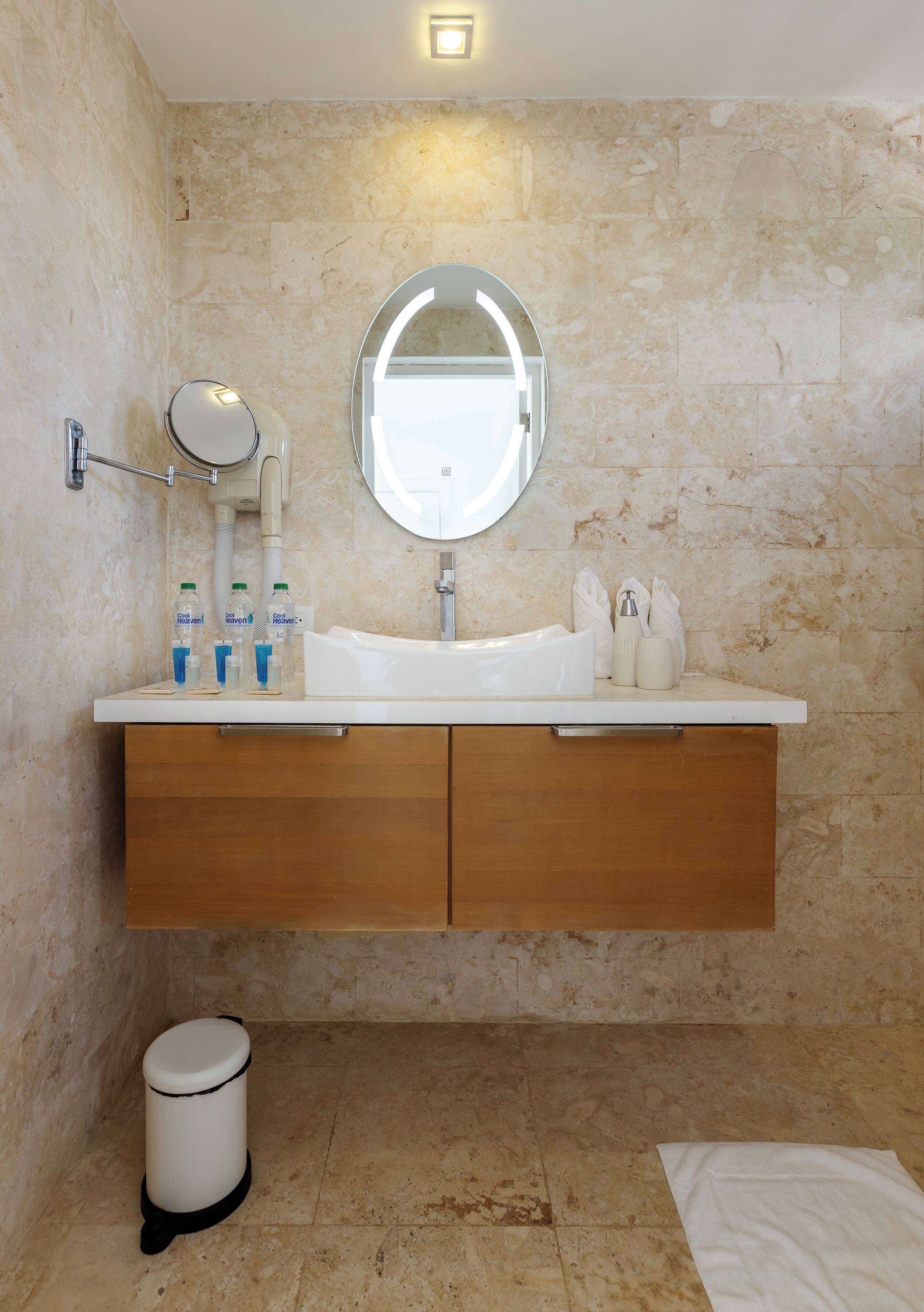 A bathroom with a marble wall, a sink with a mirror, and toiletries.