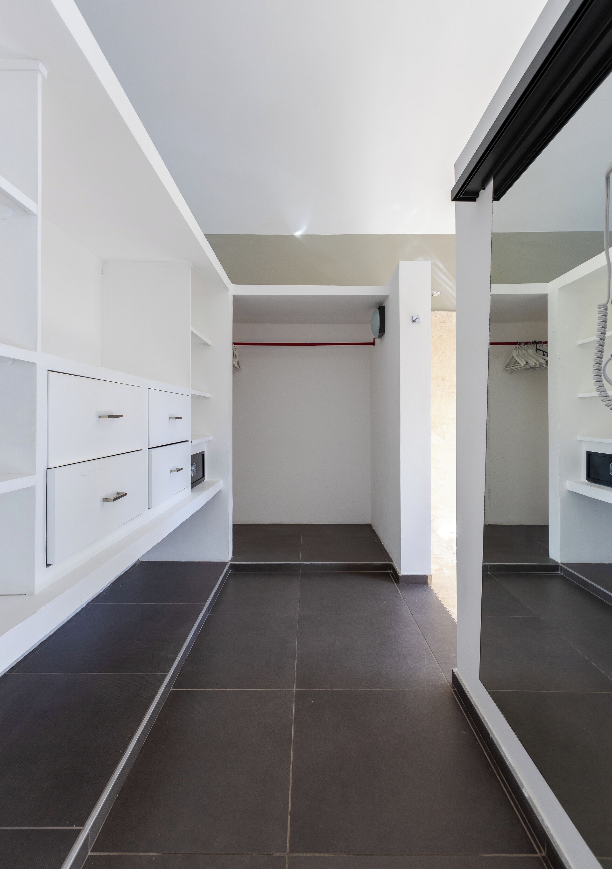 A modern walk-in closet with built-in drawers and shelves, a hanging rod, and a large mirror.