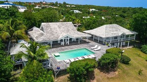 A large house with a swimming pool, surrounded by lush greenery and other houses in the background. - Whispers of the Caribbean: Villa Azur’s Private Pool, Jacuzzi & Timeless Luxury (Les Terres Basses)