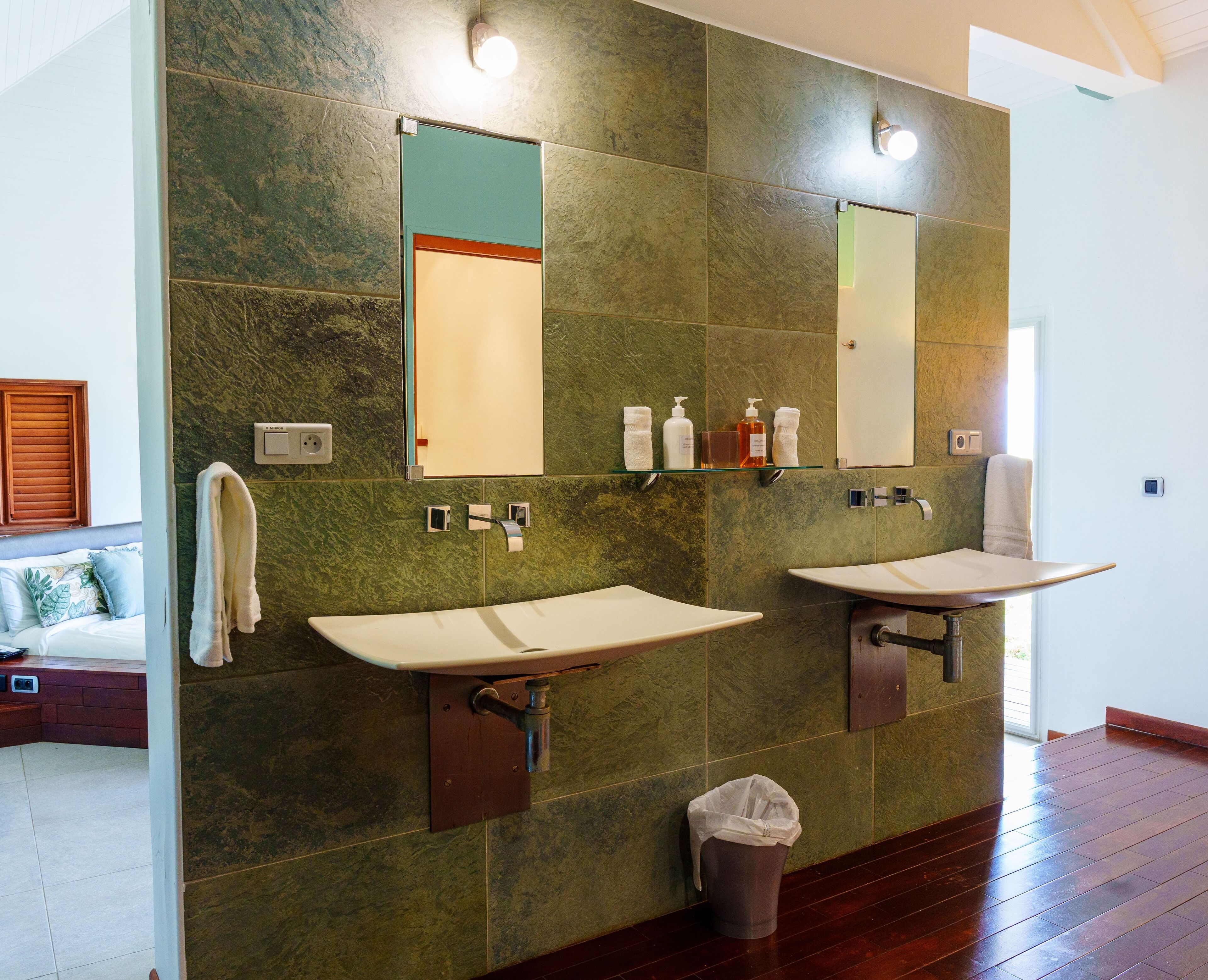 A bathroom with two sinks, a mirror, and a trash can.