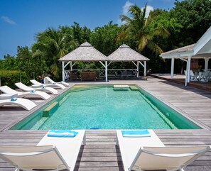A pool with lounge chairs and a gazebo.