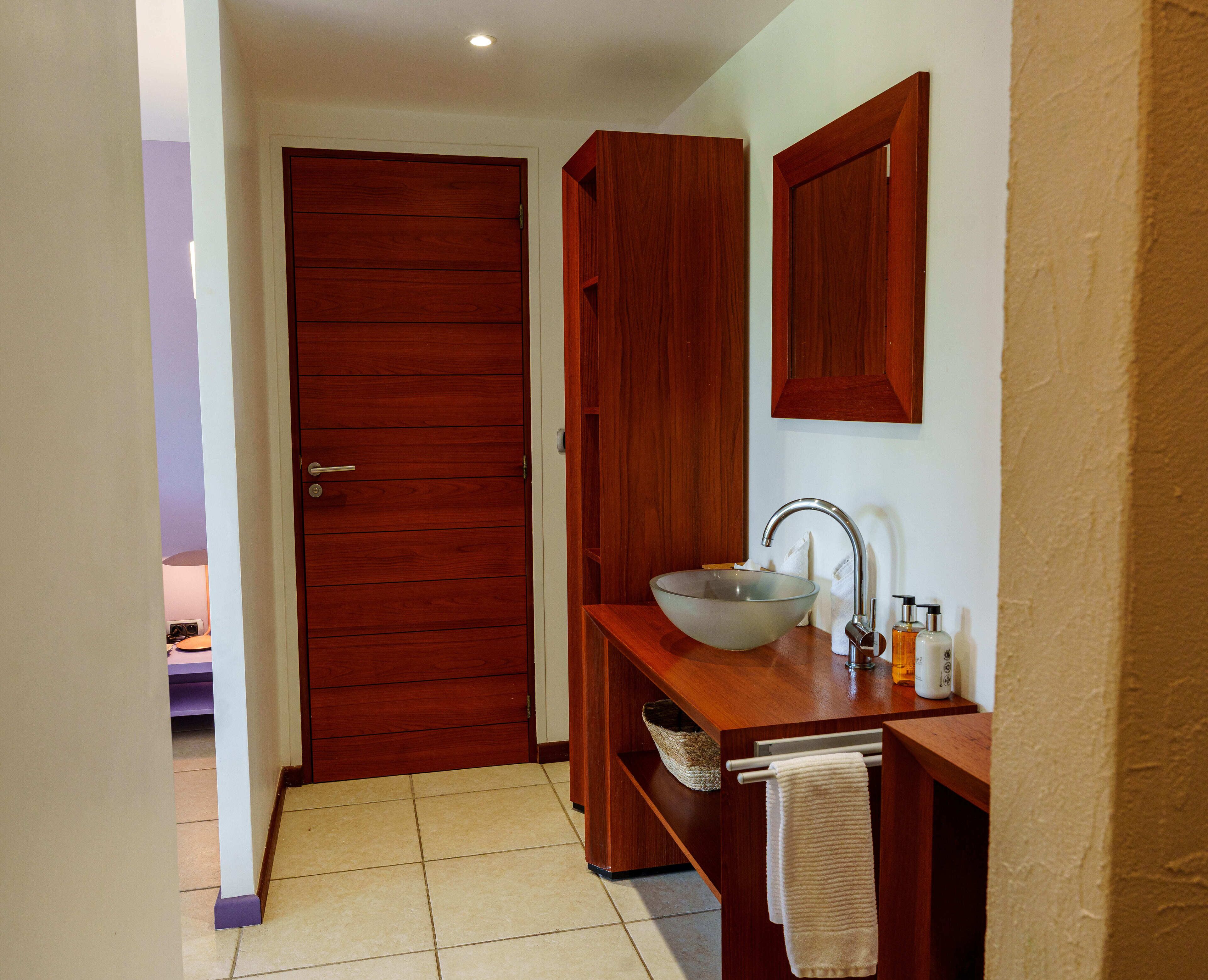 Ein Badezimmer mit Holztür, Waschbecken mit Glasbecken und Handtuchhalter.