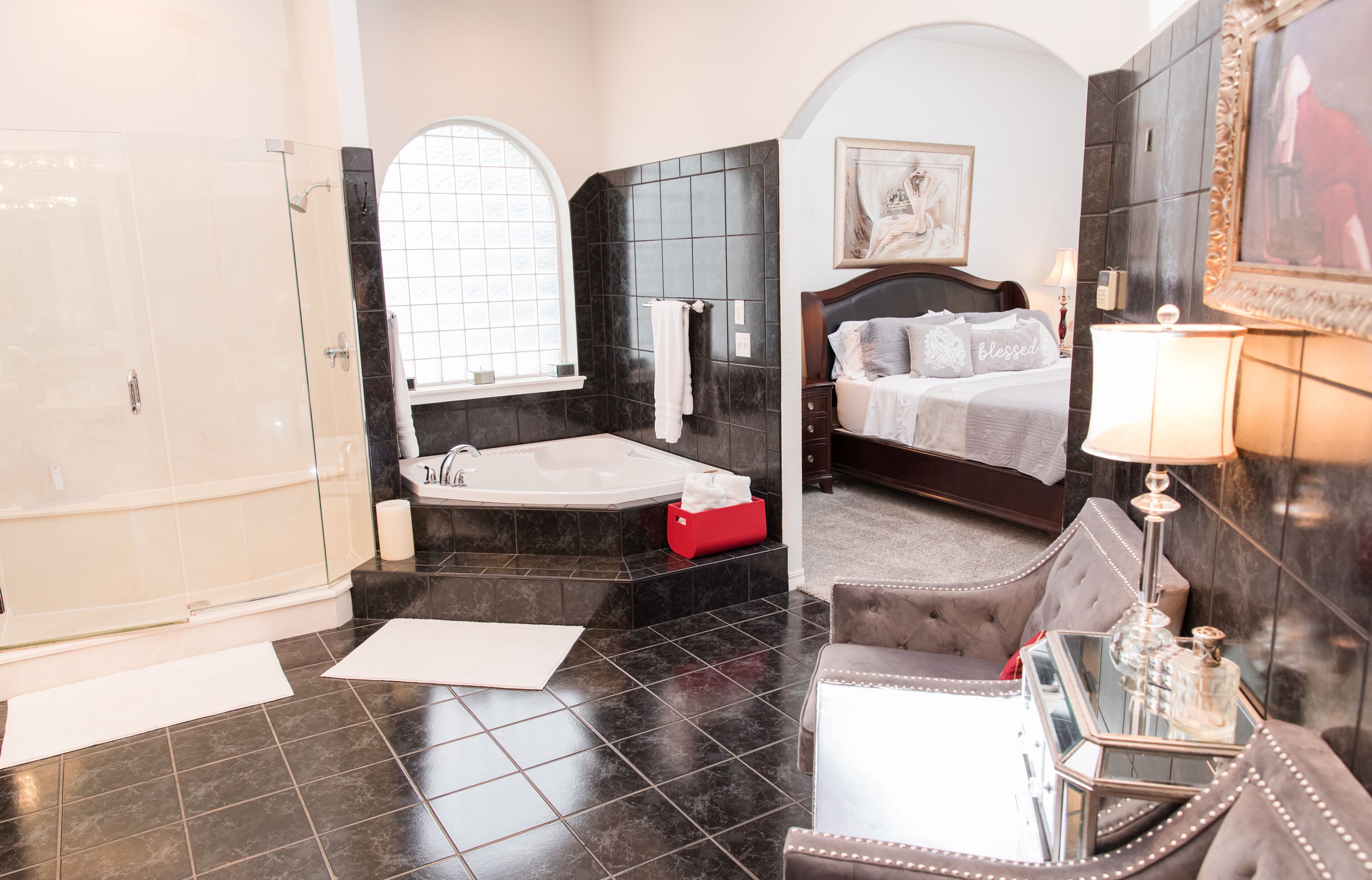 Une salle de bain luxueuse dotée d’une grande baignoire, d’une douche séparée et d’un coin salon confortable agrémenté d’un miroir et d’objets décoratifs.