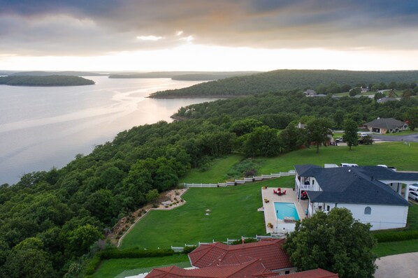 A residential area with a large body of water, lush greenery, and houses with a swimming pool.