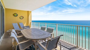 Un balcon avec une table ronde et des chaises, une balustrade et une vue sur l’océan.