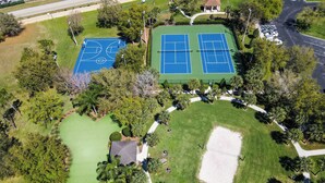 Vista aérea de un parque con canchas de tenis, un campo de golf y senderos peatonales.