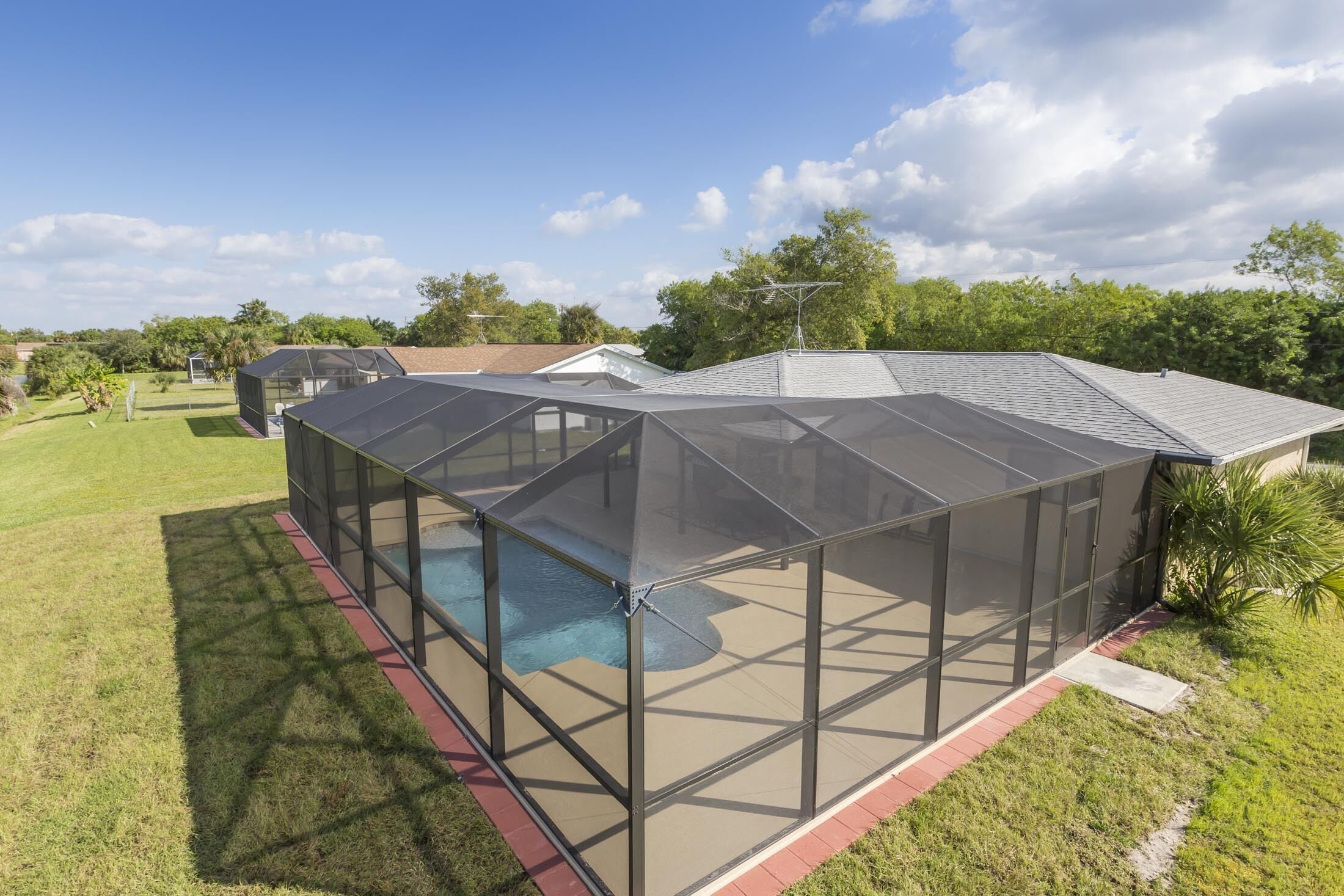 Una casa moderna con un amplio patio cubierto que da a una piscina.