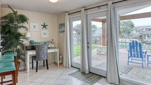 Una habitación con escritorio, silla y vista a un patio trasero con piscina y mobiliario exterior.