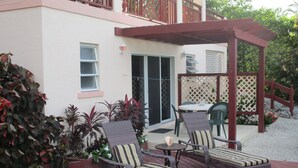 A patio with wicker furniture, a pergola, and a view of a building with a balcony. - HOOPERS BAY PRIME BEACHFRONT  KING or TWIN  STUDIO  and with STARLINK fast WIFI (Georgetown)