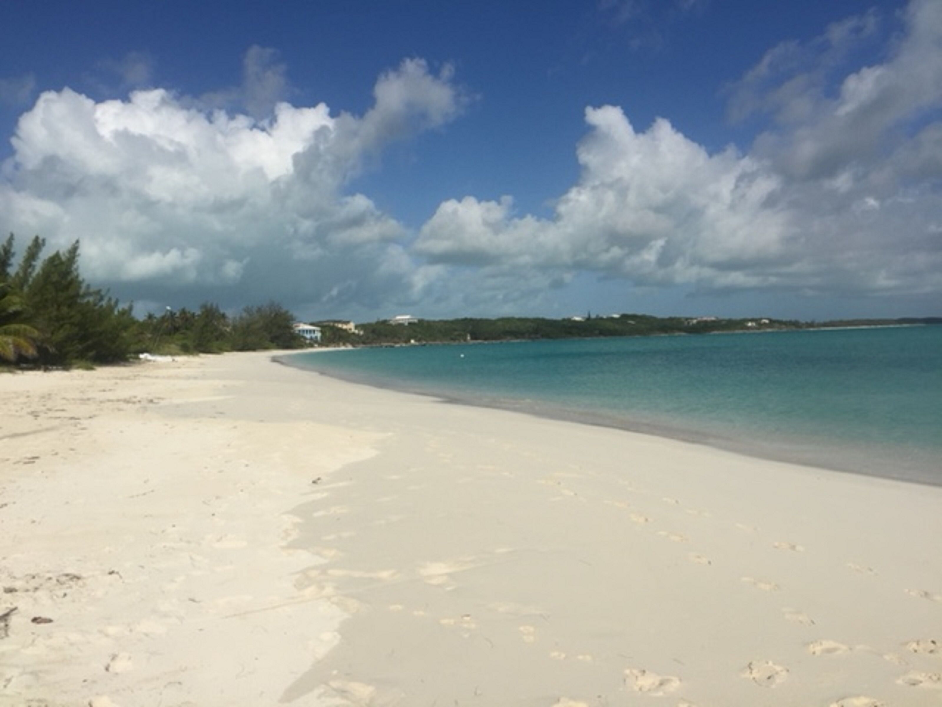 Ein Strand mit klarem türkisblauem Wasser und weißem Sand, übersät mit Fußabdrücken.