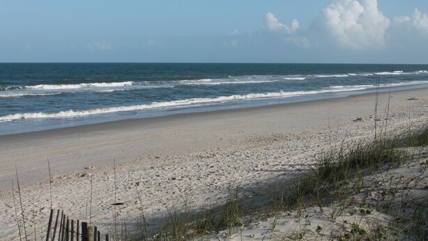 Ein Strand mit sandigem Ufer und Wellen.