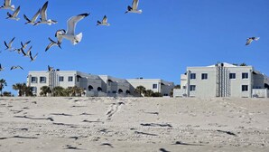 A coastal building with multiple balconies and a sandy foreground.