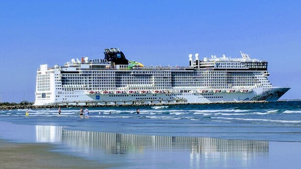 Un gran crucero amarrado en una playa con cielo despejado.