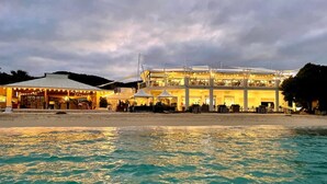 A beachfront hotel with multiple levels, outdoor seating, and a covered area.