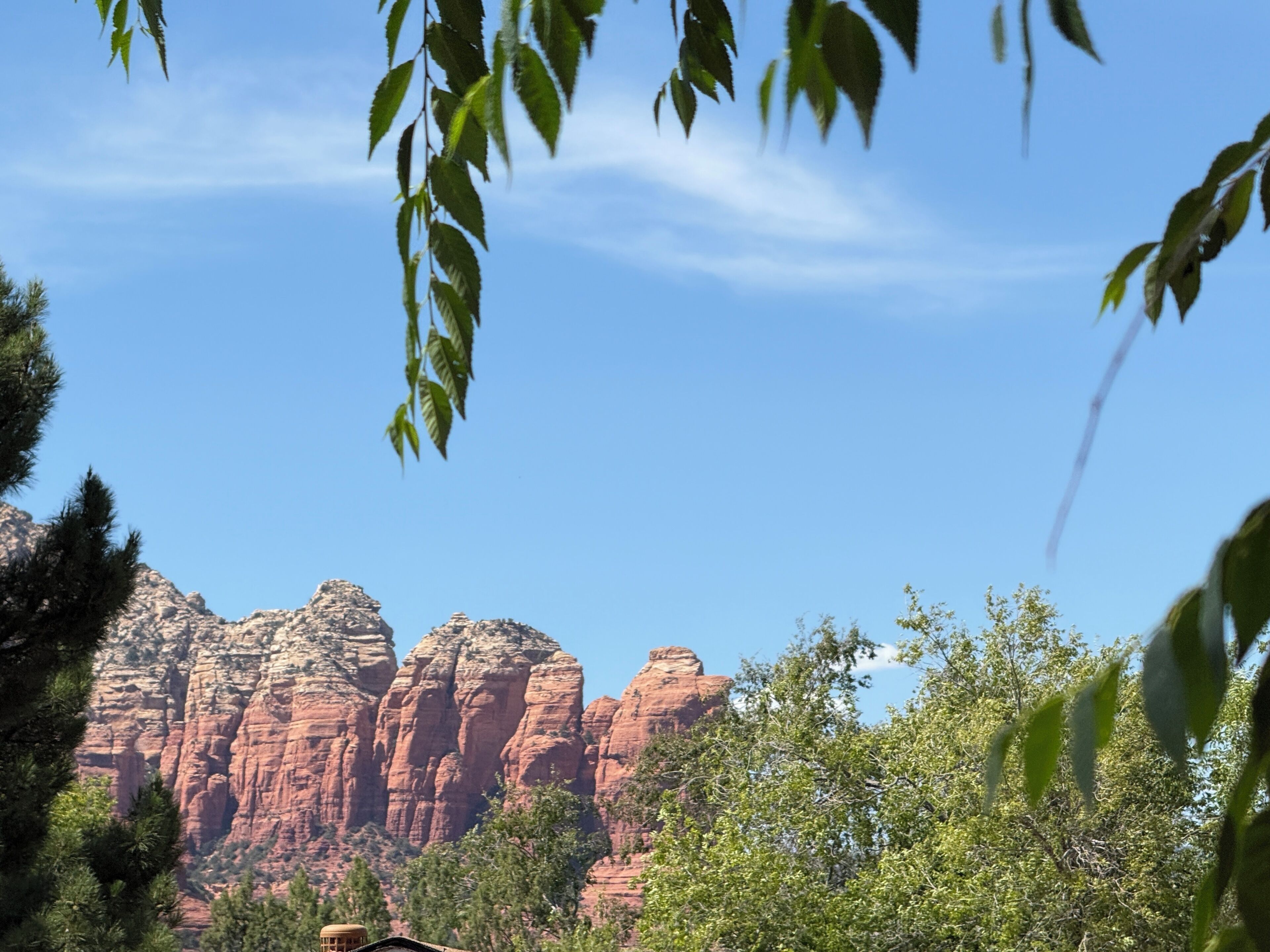 A mountain landscape with red rock formations and green trees.