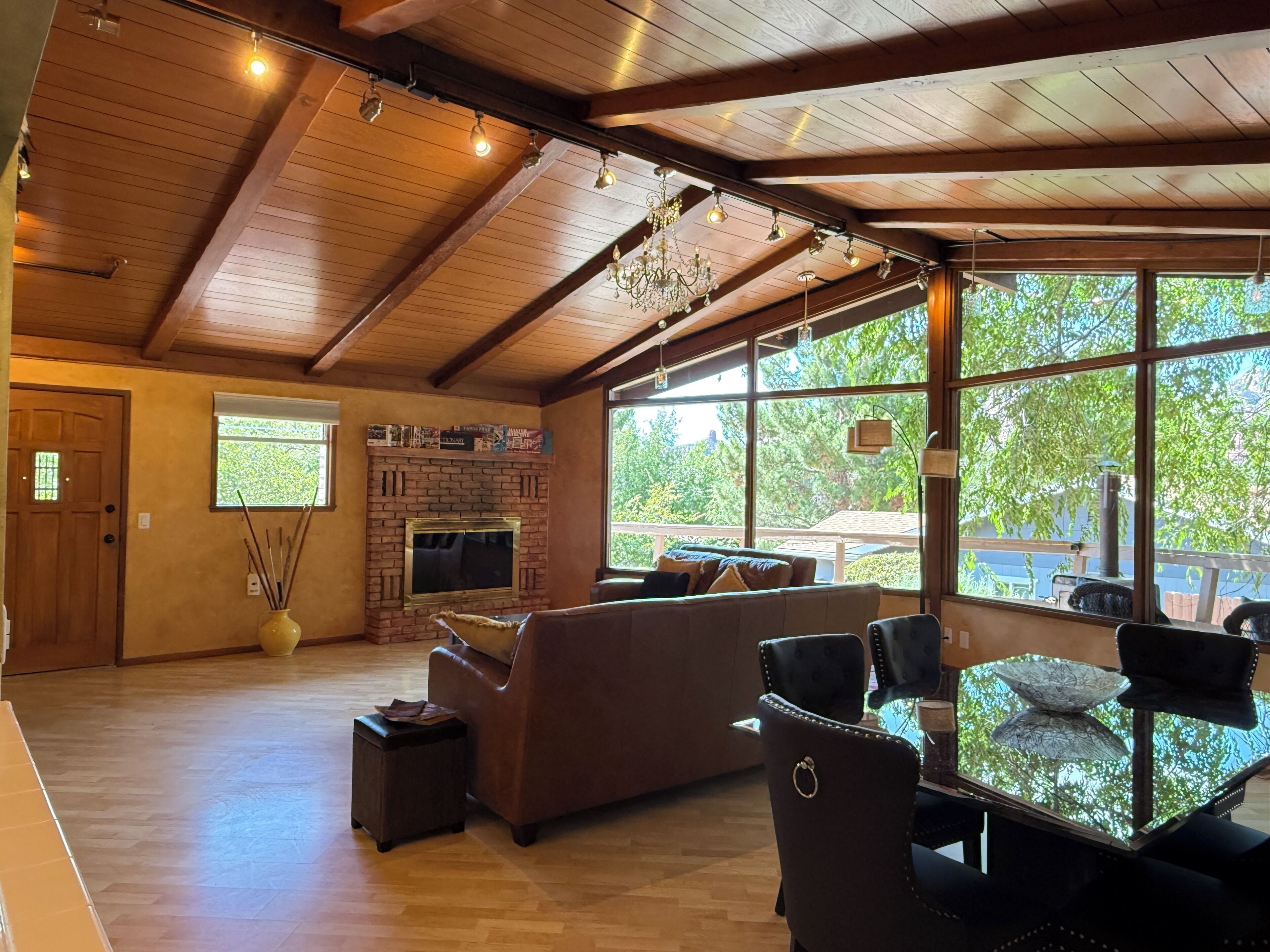 A spacious living area with a fireplace, large windows, and a high ceiling.