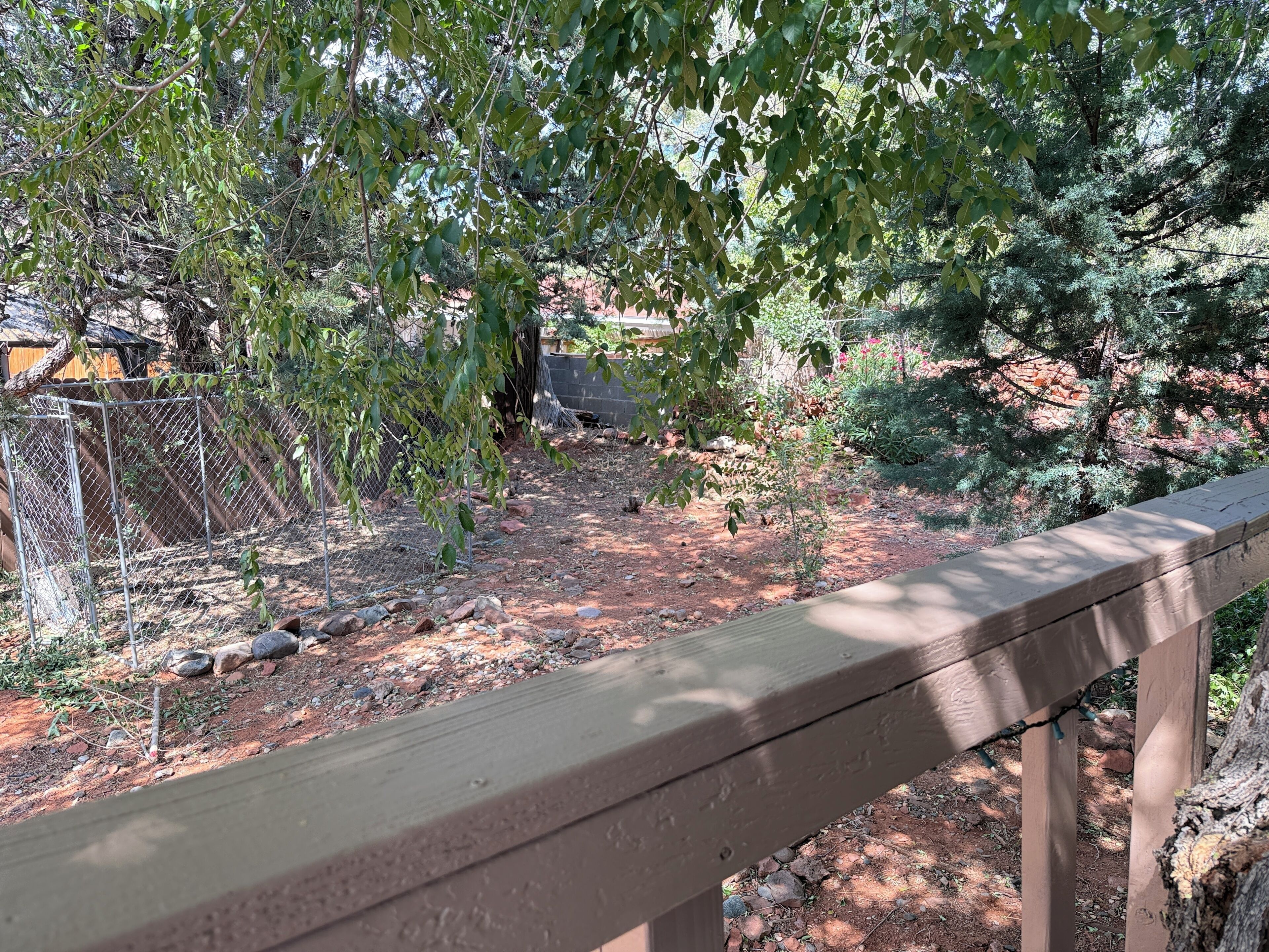 A wooden deck with a metal fence and trees in the background.
