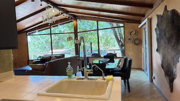 A modern kitchen with a large island, a chandelier, and a view of the outdoors.