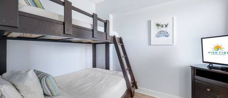 A bunk bed with a ladder, a TV, and a framed picture on the wall.