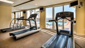 Un gimnasio con cintas de correr y vistas a la piscina.