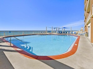 Relax by the pool surrounded by comfortable lounge chairs and umbrellas.