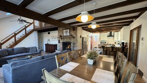Ein geräumiges Wohnzimmer mit einem großen Holzesstisch, grauen Sofas und einem Kamin.