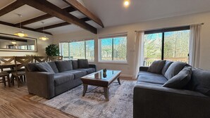 Ein geräumiges Wohnzimmer mit einer großen Sofagarnitur, einem Couchtisch und einem Essbereich mit Holztisch und Stühlen.