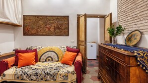 Une pièce avec un canapé à motifs, un meuble en bois, un miroir et un tableau accroché au mur.