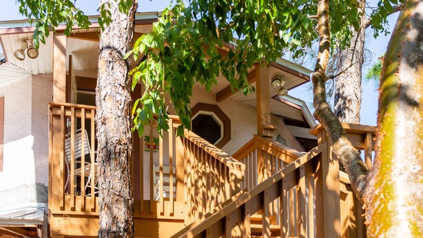 Una escalera de madera con barandilla que conduce a un edificio con varios pisos y balcones.
