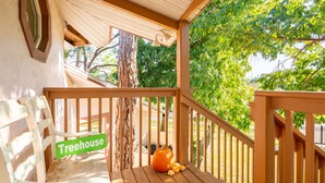 Una terraza de madera con un banco que dice "Treehouse", una calabaza grande y un árbol al fondo.