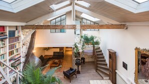 A spacious loft with a high ceiling, skylights, a staircase, and a library filled with books. - Huge loft, full of light, in the lively Canal Saint-Martin, near Marais area (Paris)