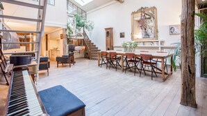 A spacious room with a piano, a dining table with chairs, a staircase, and a large mirror on the wall. - Huge loft, full of light, in the lively Canal Saint-Martin, near Marais area (Paris)