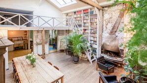 A spacious loft with a high ceiling, exposed brick walls, a large wooden dining table, and a cozy fireplace. - Huge loft, full of light, in the lively Canal Saint-Martin, near Marais area (Paris)