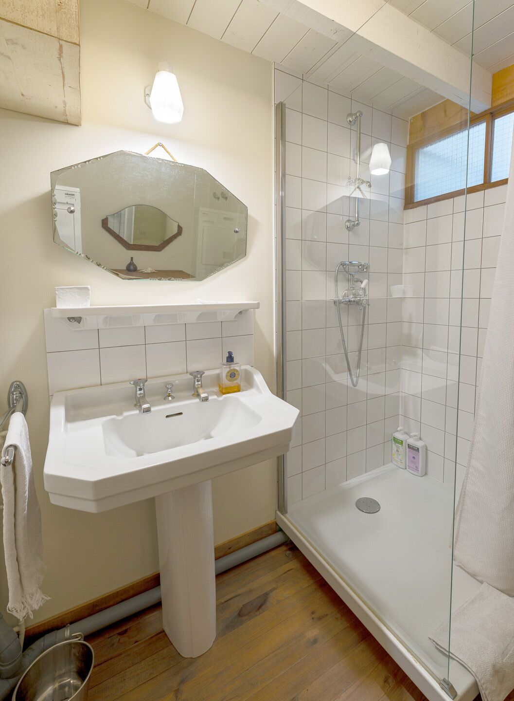 A bathroom with a white sink, mirror, and shower.