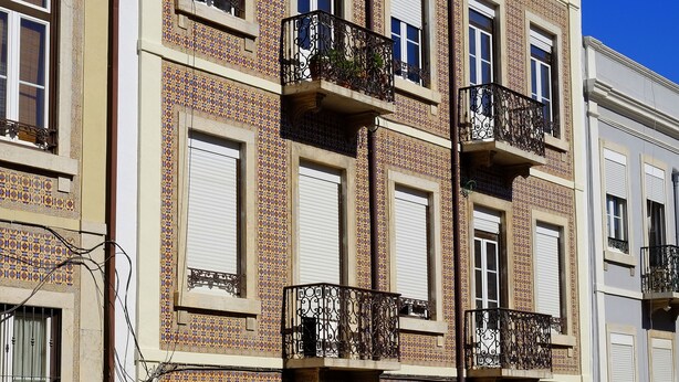 A multi-story building with a tiled facade, balconies, and a central arched entrance. - Travessa House I - Graça. Lisbon Historic Center (Lisbon)